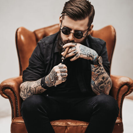 Young man smoking cigar in leather chair